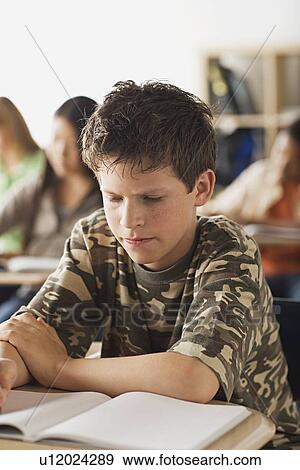 Serious schoolboy sitting in classroom View Large Photo Image Stock Photo - Serious schoolboy sitting in classroom. Fotosearch