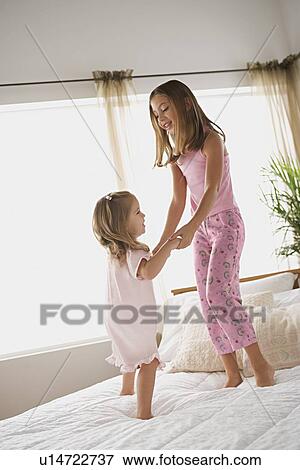 Sisters (8-9, 12-13) jumping on bed View Large Photo Image Stock Photo - Sisters (8-9, 12-13) jumping on bed. Fotosearch