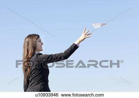 Stock Photograph - Smiling businesswoman throwing paper plane. Fotosearch