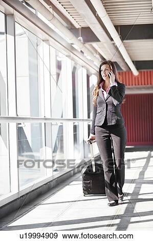 Smiling businesswoman walking with suitcase View Large Photo Image Stock Photo - Smiling businesswoman walking with suitcase. Fotosearch