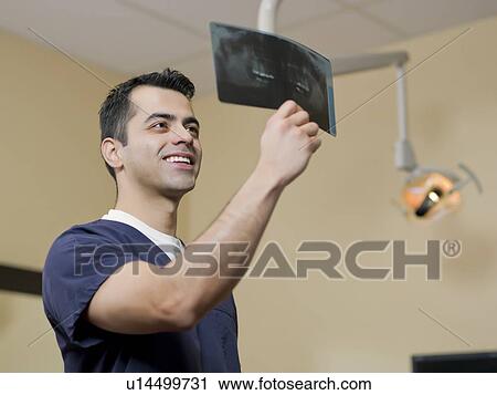 Smiling dentist in surgery checking x-ray View Large Photo Image Stock Image - Smiling dentist in surgery checking x-ray . Fotosearch
