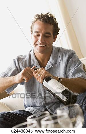 Stock Photography - Smiling man opening bottle of wine. Fotosearch