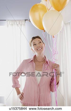 Smiling mature woman holding balloons View Large Photo Image Picture - Smiling mature woman holding balloons. Fotosearch