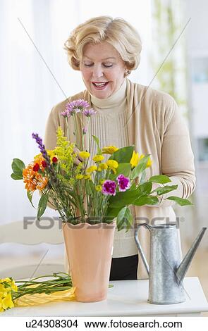 Smiling senior woman arranging flowers View Large Photo Image Picture - Smiling senior woman arranging flowers. Fotosearch