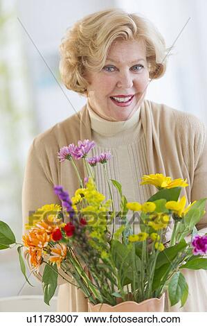 Smiling senior woman arranging flowers View Large Photo Image Stock Photo - Smiling senior woman arranging flowers. Fotosearch