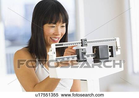 Smiling woman checking her weight View Large Photo Image Stock Photography - Smiling woman checking her weight. Fotosearch