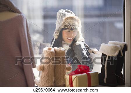 Picture - Smiling woman looking at shop display during Christmas shopping. Fotosearch
