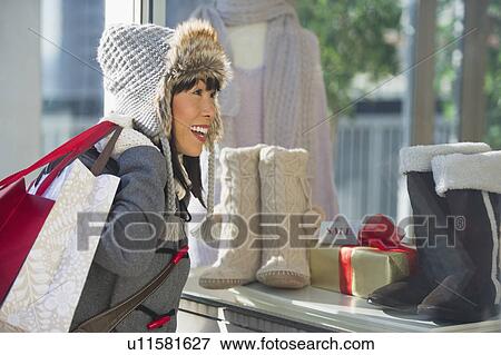 Stock Photo - Smiling woman looking at shop display during Christmas shopping. Fotosearch