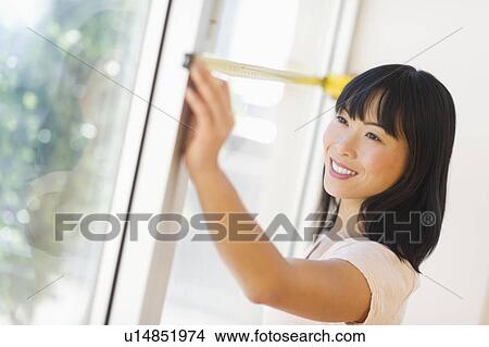 Picture - Smiling woman measuring window . Fotosearch