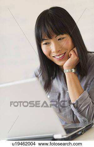 Picture - Smiling woman using laptop. Fotosearch