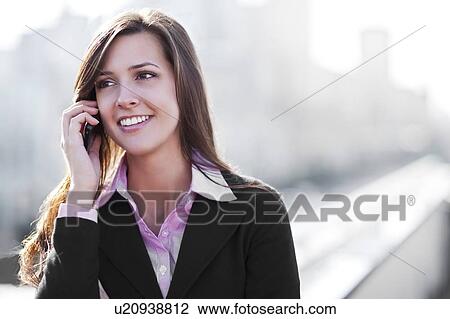 Smiling young businesswoman talking via mobile View Large Photo Image Stock Image - Smiling young businesswoman talking via mobile. Fotosearch