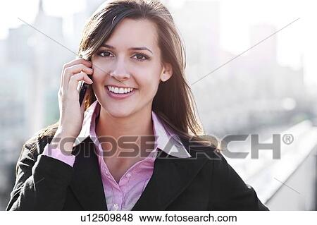 Smiling young businesswoman talking via mobile View Large Photo Image Stock Photo - Smiling young businesswoman talking via mobile. Fotosearch