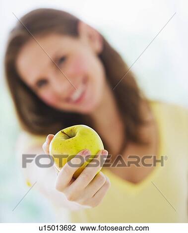 Smiling young woman holding apple View Large Photo Image Stock Image - Smiling young woman holding apple. Fotosearch
