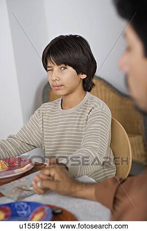 Picture - Son looking at father during prayer before meal. Fotosearch