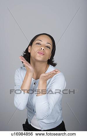 Stock Photograph - Studio portrait of attractive mid adult woman blowing kiss. Fotosearch