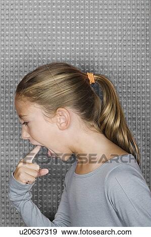 Stock Photo - Studio portrait of girl (12-13) inserting finger in mouth. Fotosearch