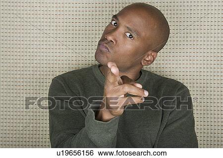 Stock Photograph - Studio portrait of mid adult man pointing at camera. Fotosearch