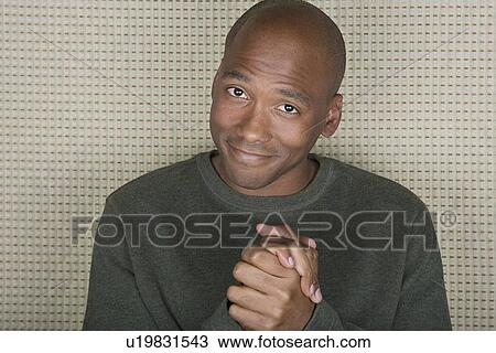 Stock Image - Studio portrait of mid adult man with hands clasped. Fotosearch