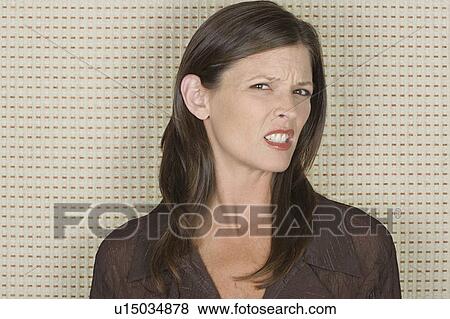 Studio portrait of mid adult woman grimacing View Large Photo Image Stock Photo - Studio portrait of mid adult woman grimacing. Fotosearch