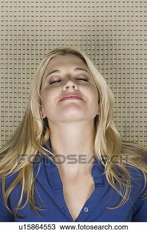 Stock Image - Studio portrait of mid adult woman with eyes closed. Fotosearch