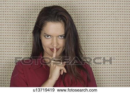 Studio portrait of mid adult woman with finger on lips View Large Photo Image Stock Photo - Studio portrait of mid adult woman with finger on lips. Fotosearch