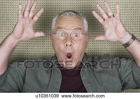 Stock Photo - Studio portrait of senior man with arms raised. Fotosearch
