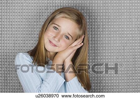 Stock Image - Studio portrait of teen (16-17) girl resting head on hands. Fotosearch