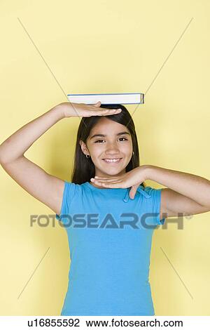 Studio portrait of teenage (16-17) girl balancing book on head View Large Photo Image Stock Image - Studio portrait of teenage (16-17) girl balancing book on head. Fotosearch