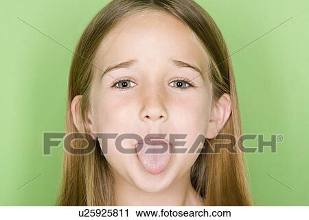 Stock Image - Studio portrait of teenage (16-17) girl sticking out tongue. Fotosearch