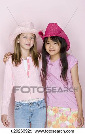 Stock Photography - Studio portrait of two teenage (16-17) girls wearing cowboy hats. Fotosearch