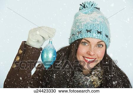 Studio portrait of woman in winter clothing holding Christmas ornament View Large Photo Image Stock Image - Studio portrait of woman in winter clothing holding Christmas ornament. Fotosearch
