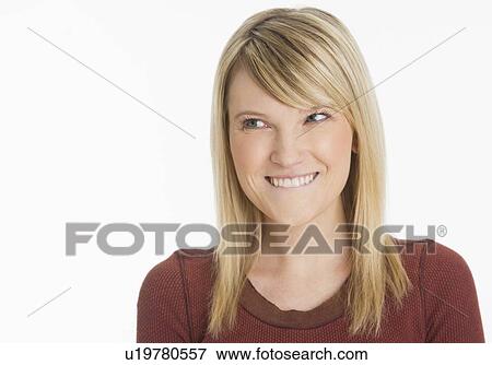 Studio portrait of woman smiling and biting lip View Large Photo Image Stock Photo - Studio portrait of woman smiling and biting lip. Fotosearch