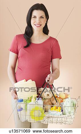 Studio portrait of woman with shopping basket full of baby goods View Large Photo Image Stock Photo - Studio portrait of woman with shopping basket full of baby goods. Fotosearch