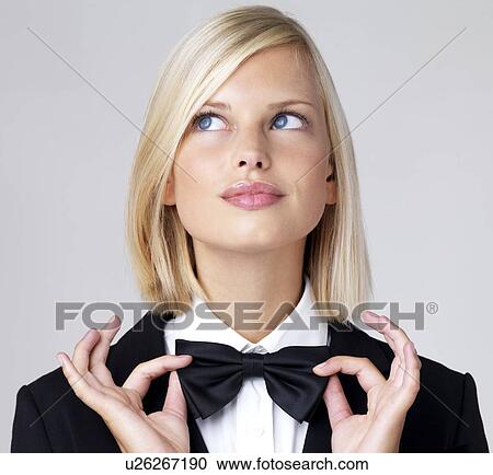 Stock Image - Studio portrait of young waitress adjusting bow tie. Fotosearch