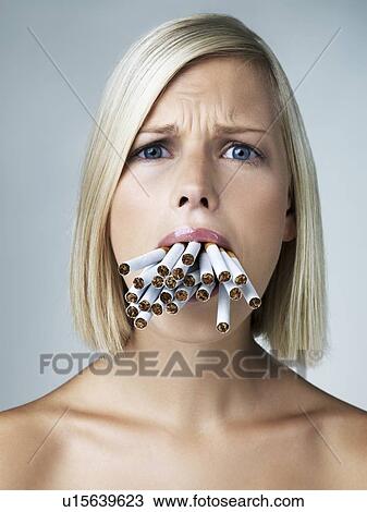 Studio portrait of young woman with mouthful of cigarettes View Large Photo Image Stock Image - Studio portrait of young woman with mouthful of cigarettes. Fotosearch