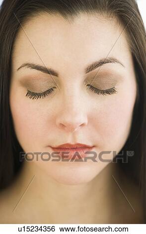 Stock Photograph - Studio portrait of young woman with eyes shut. Fotosearch