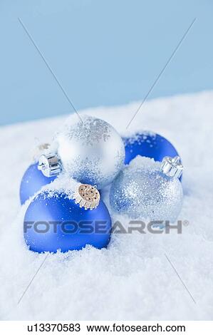 Stock Image - Studio shot of blue and silver christmas ornament on snow. Fotosearch
