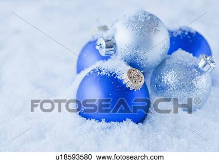 Stock Image - Studio shot of blue and silver Christmas ornament on snow. Fotosearch