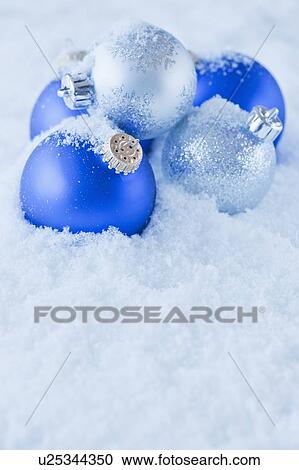 Stock Image - Studio shot of blue and silver Christmas ornament on snow. Fotosearch