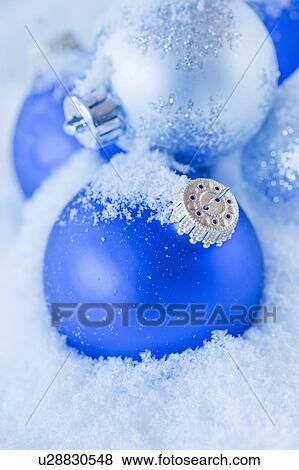 Stock Photo - Studio shot of blue and silver Christmas ornament on snow. Fotosearch