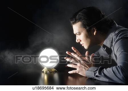 Picture - Studio shot of businessman looking at crystal ball. Fotosearch