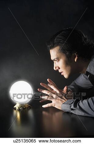Stock Photography - Studio shot of businessman looking at crystal ball. Fotosearch