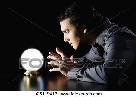 Stock Photo - Studio shot of businessman staring at crystal ball. Fotosearch