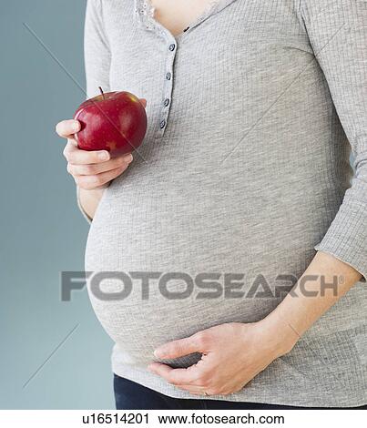 Studio shot of pregnant woman eating apple, midsection View Large Photo Image Stock Image - Studio shot of pregnant woman eating apple, midsection. Fotosearch