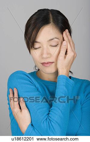 Stock Image - Studio shot of Vietnamese woman day dreaming. Fotosearch