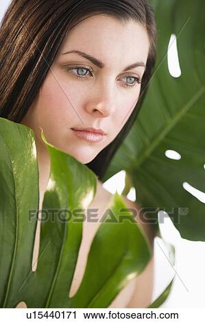 Stock Image - Studio shot of woman between leaves. Fotosearch