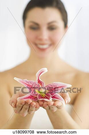 Stock Photo - Studio shot of woman holding lily. Fotosearch