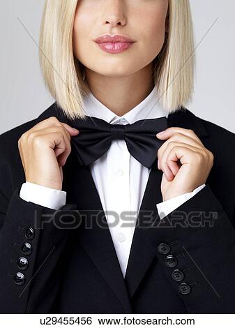 Stock Photograph - Studio shot of young waitress adjusting bow tie. Fotosearch