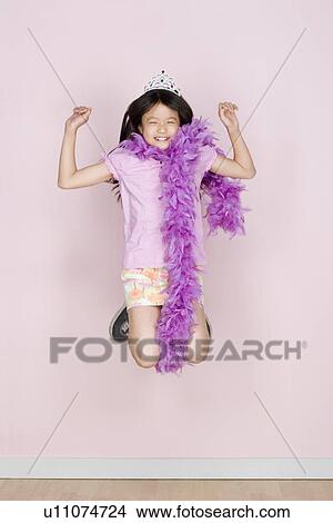 Picture - Studio shot portrait of jumping teenage girl in diadem and feather boa shawl, full length. Fotosearch