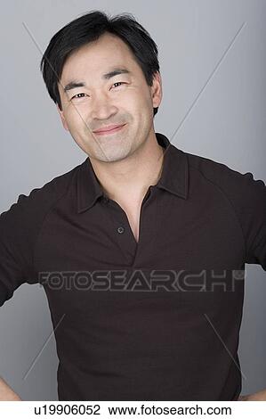 Stock Image - Studio shot portrait of mature man, waist up. Fotosearch